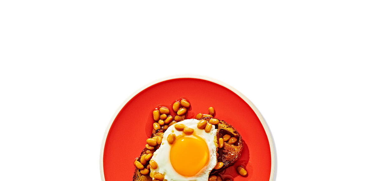 Red plate with an egg and brown beans on it